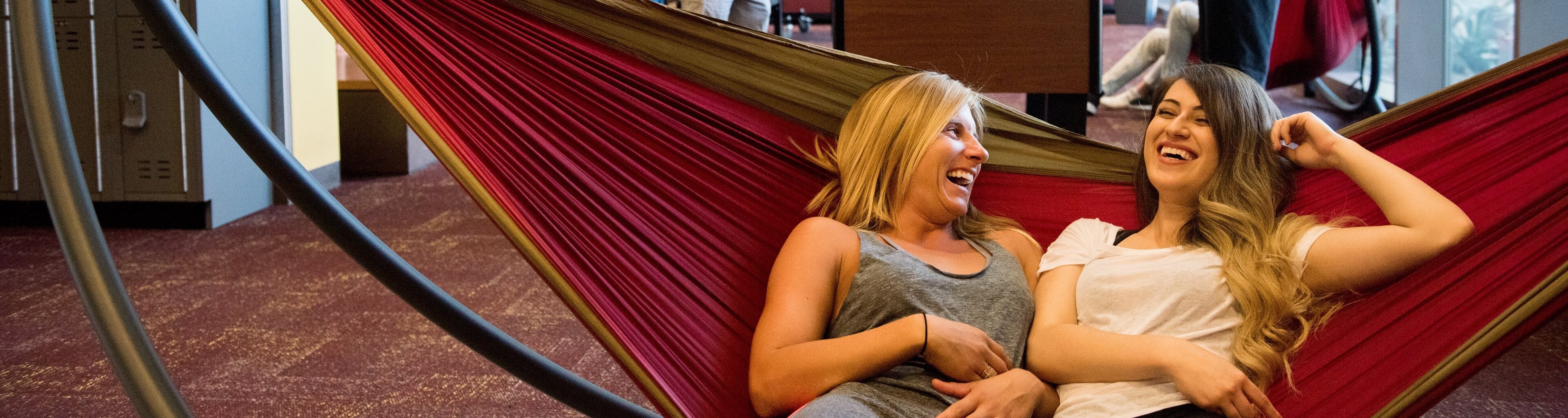 Students laughing while resting on a hammock