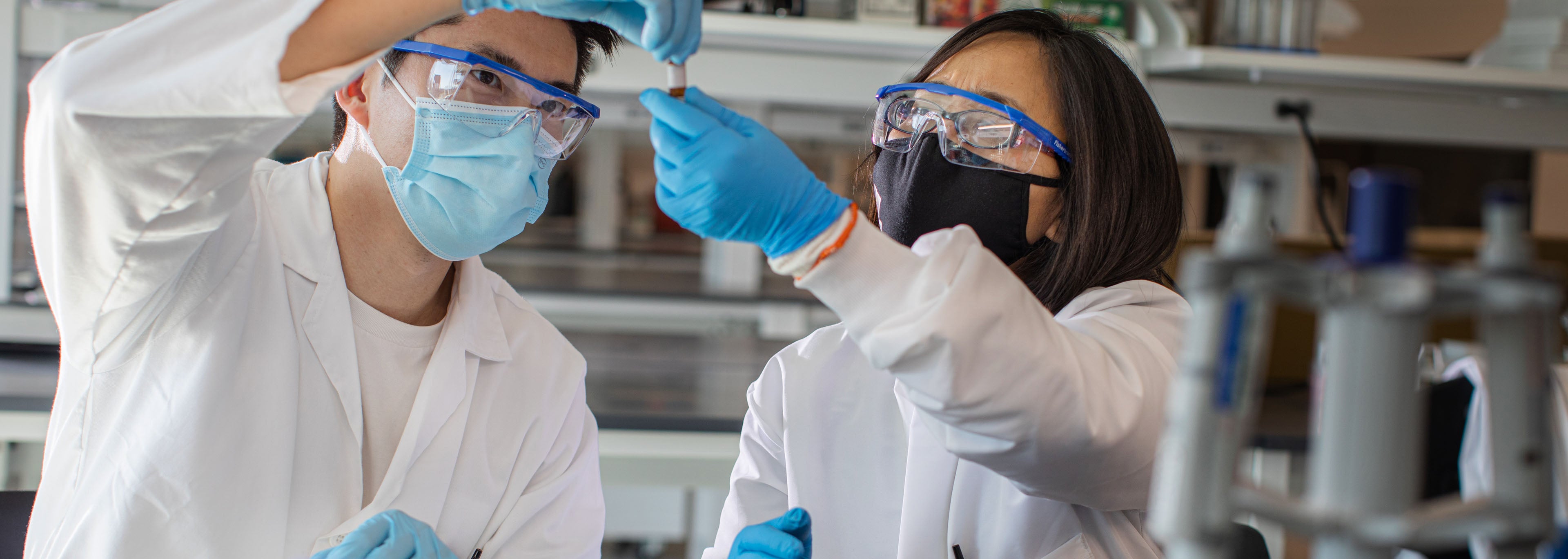 Researchers in PPE inspect a test tube