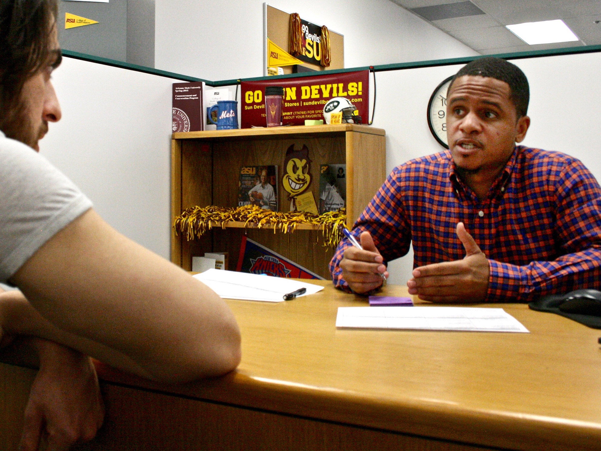 An academic advisor meeting with a student at a desk